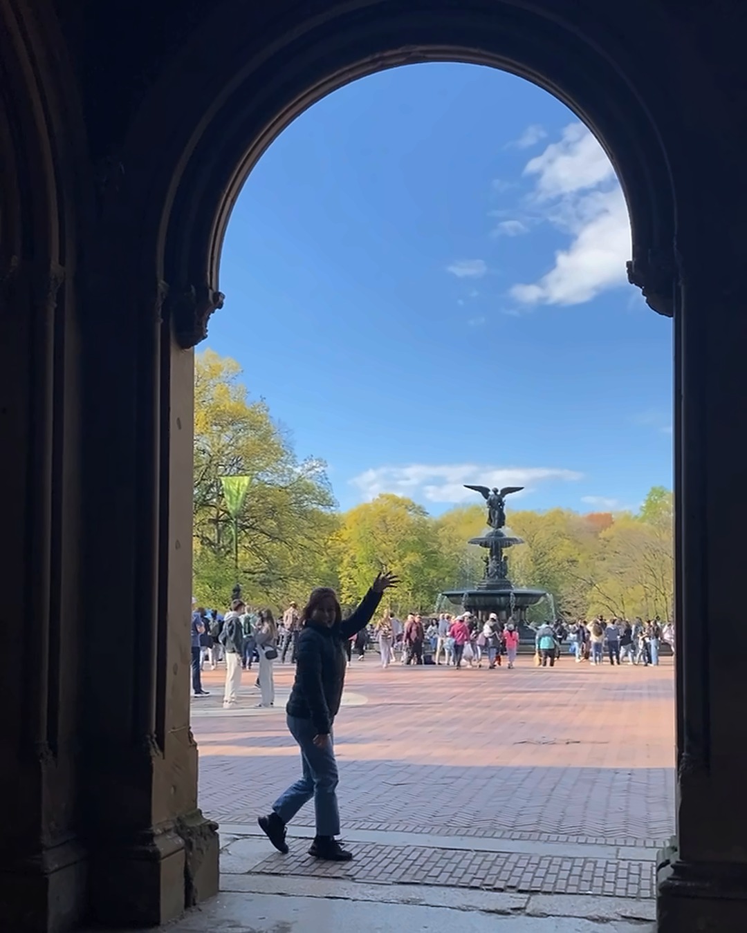 Isel Makapugay waving hello beneath a stone arch at Bethesda Terrace, Central Park