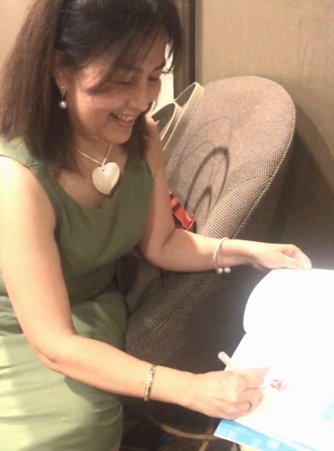 Isel Makapugay signing a copy of Big Red at a book signing event